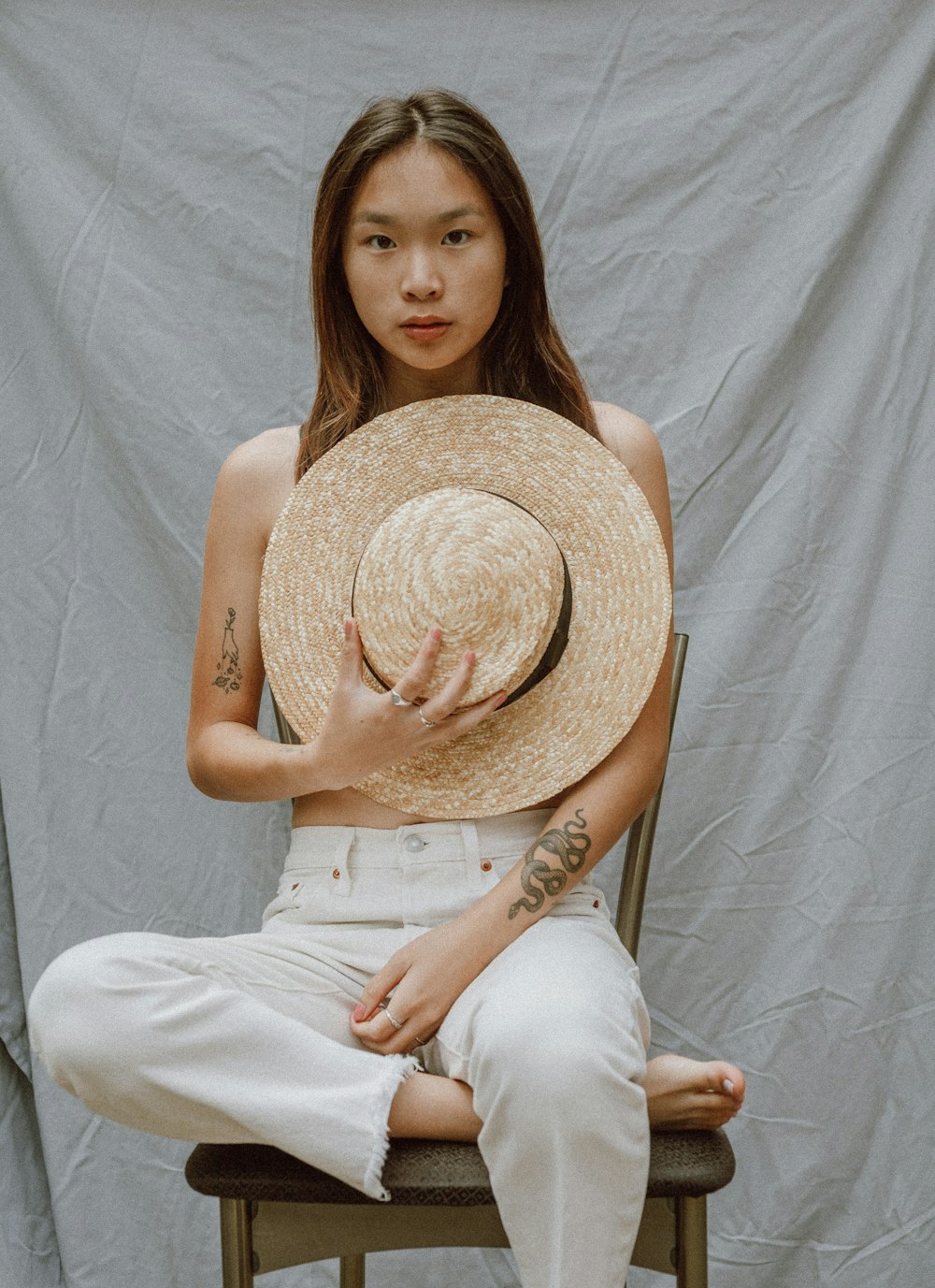 woman in white tank top and white pants wearing brown straw hat