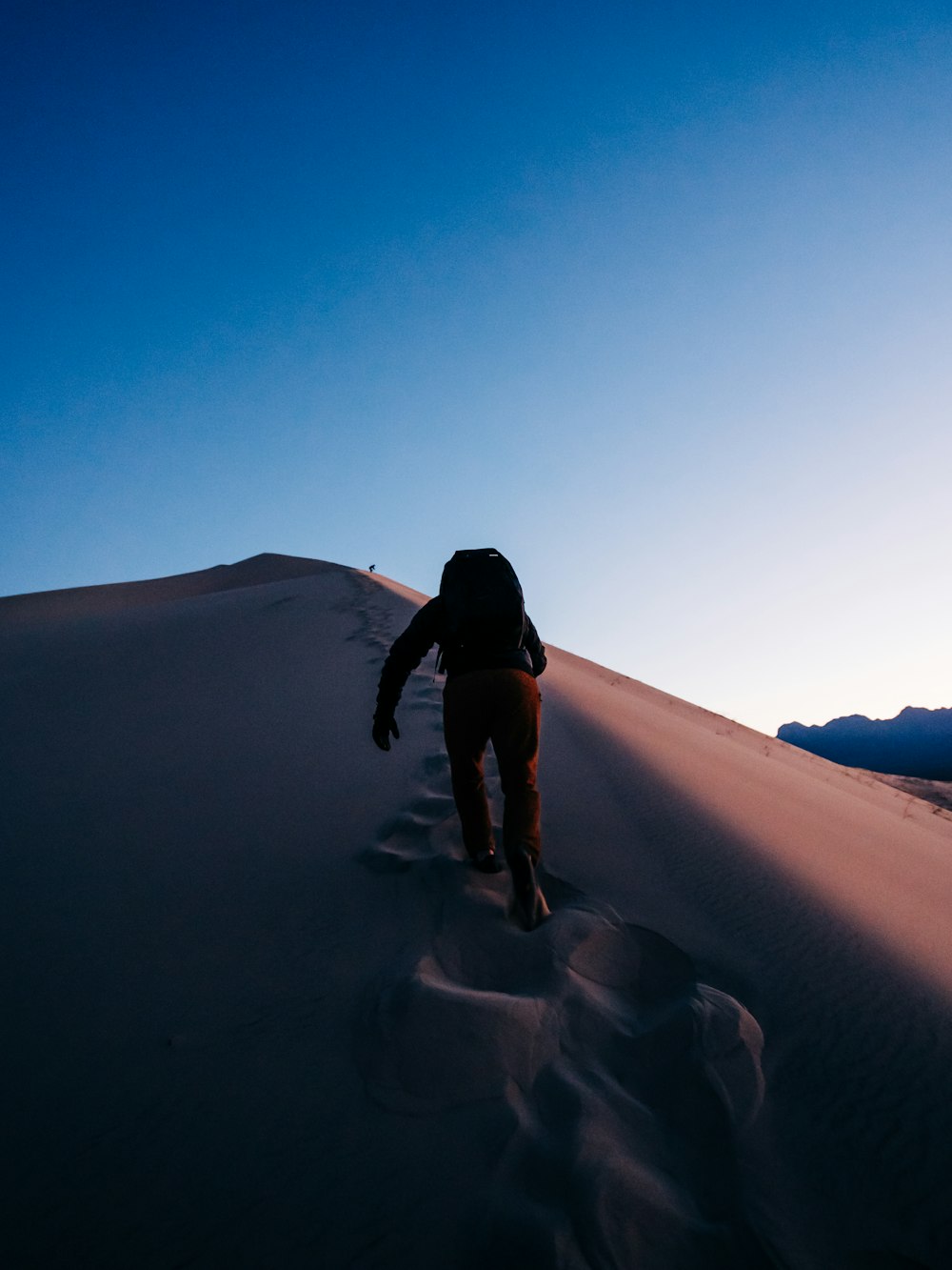 woman in black shirt and black pants walking on sand during daytime