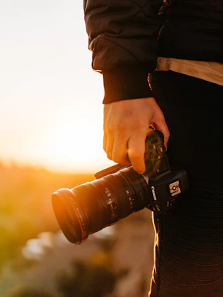 A candid portrait of Alain Abellard holding his camera in a sunlit outdoor setting.