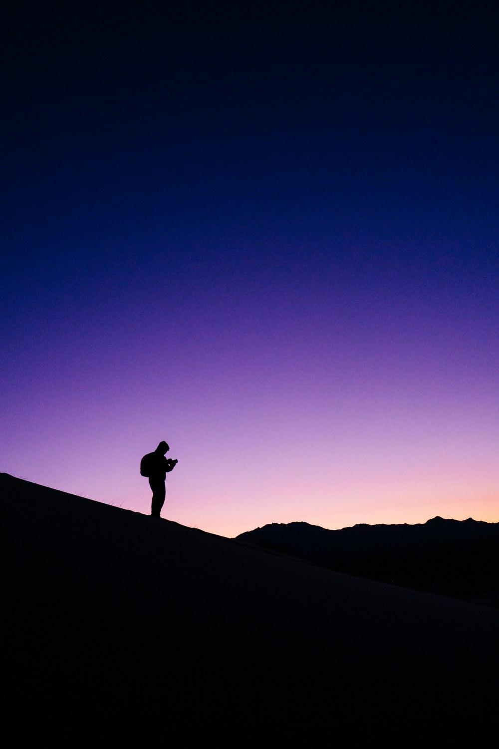 silhouette of person standing on rock formation during night time