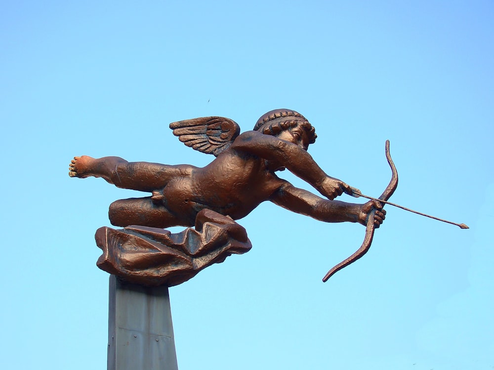 brown statue of man holding stick