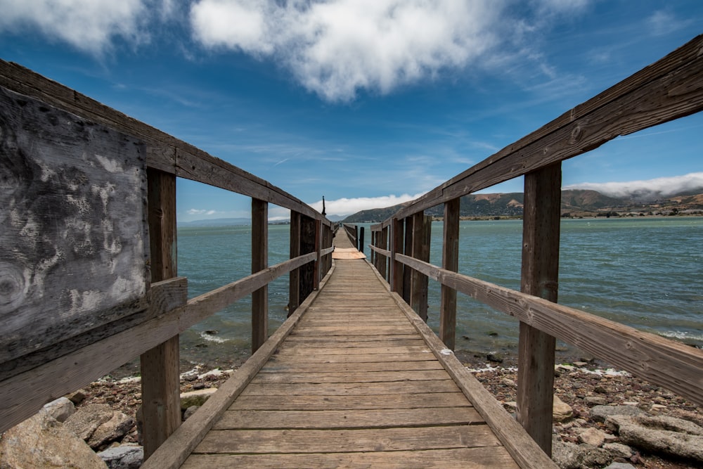 brown wooden dock on sea under blue sky and white clouds during daytime