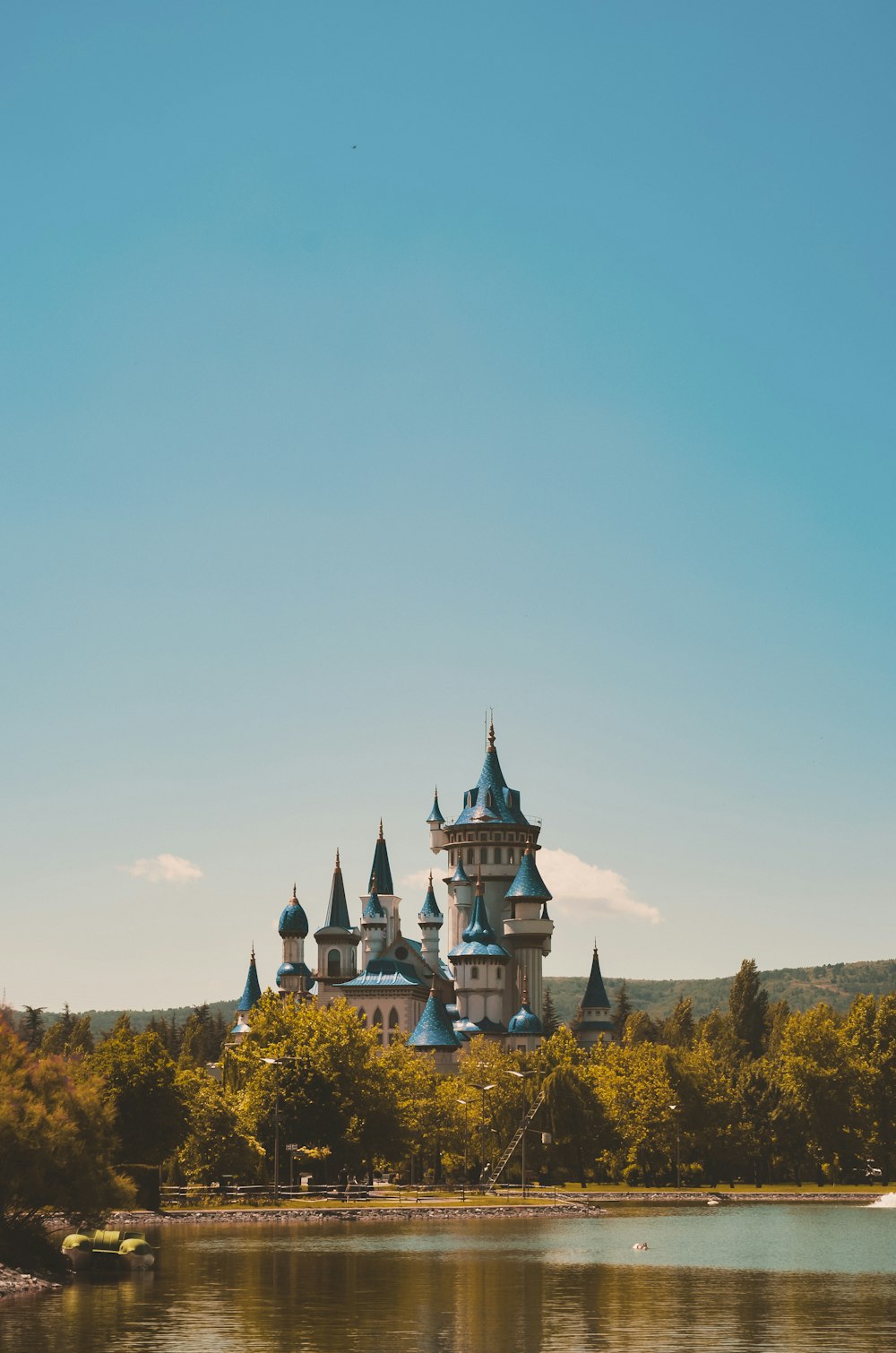 white and blue castle surrounded by green trees under blue sky during daytime