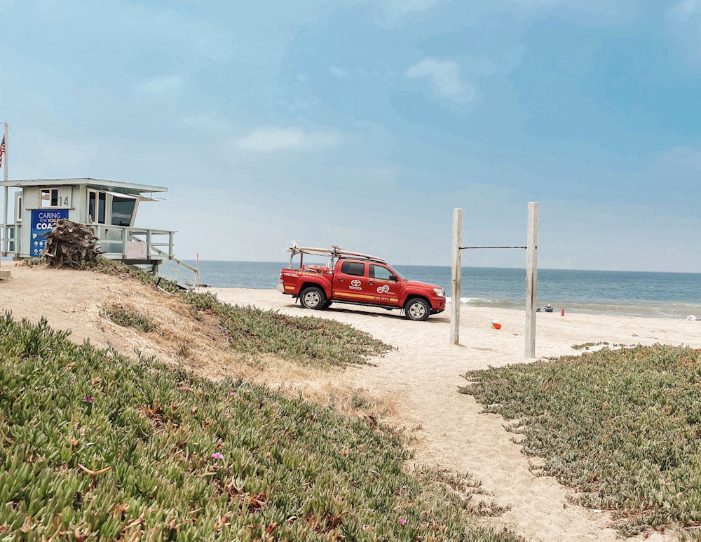 SUV rojo en la orilla de la playa durante el día