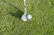 Close-up of pristine, polished golf clubs resting on lush green grass next to a worn golf glove.