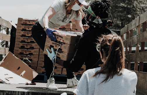 woman in white t-shirt and blue denim jeans sitting on brown cardboard box