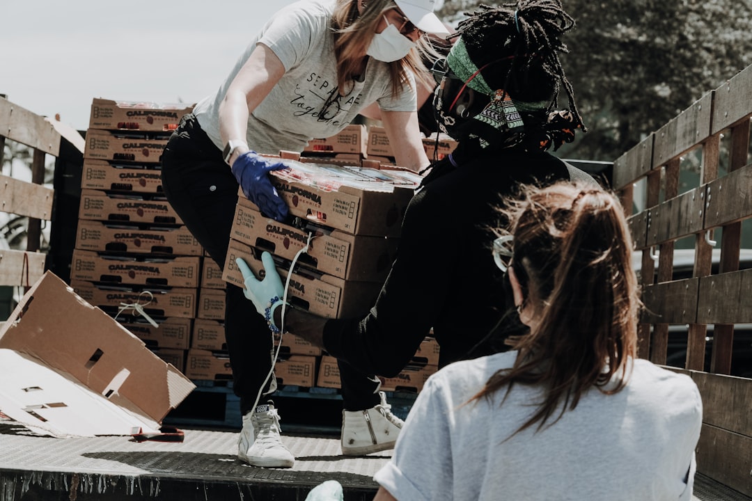 woman in white t-shirt and blue denim jeans sitting on brown cardboard box