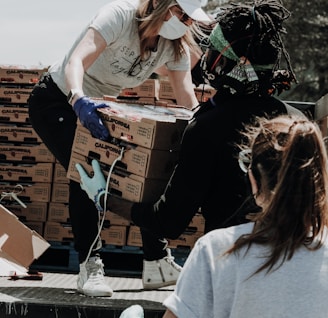 woman in white t-shirt and blue denim jeans sitting on brown cardboard box