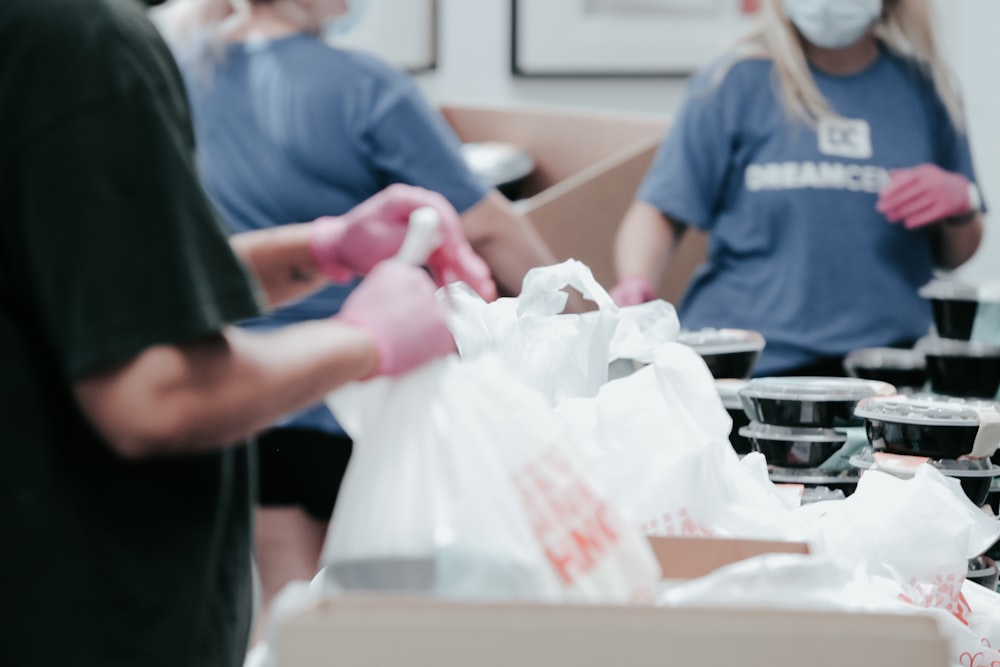 pessoa na camiseta azul do pescoço da tripulação segurando o saco plástico branco