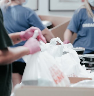 person in blue crew neck t-shirt holding white plastic bag