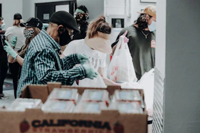 Volunteers handing out fresh food packages to smiling families at a community center.