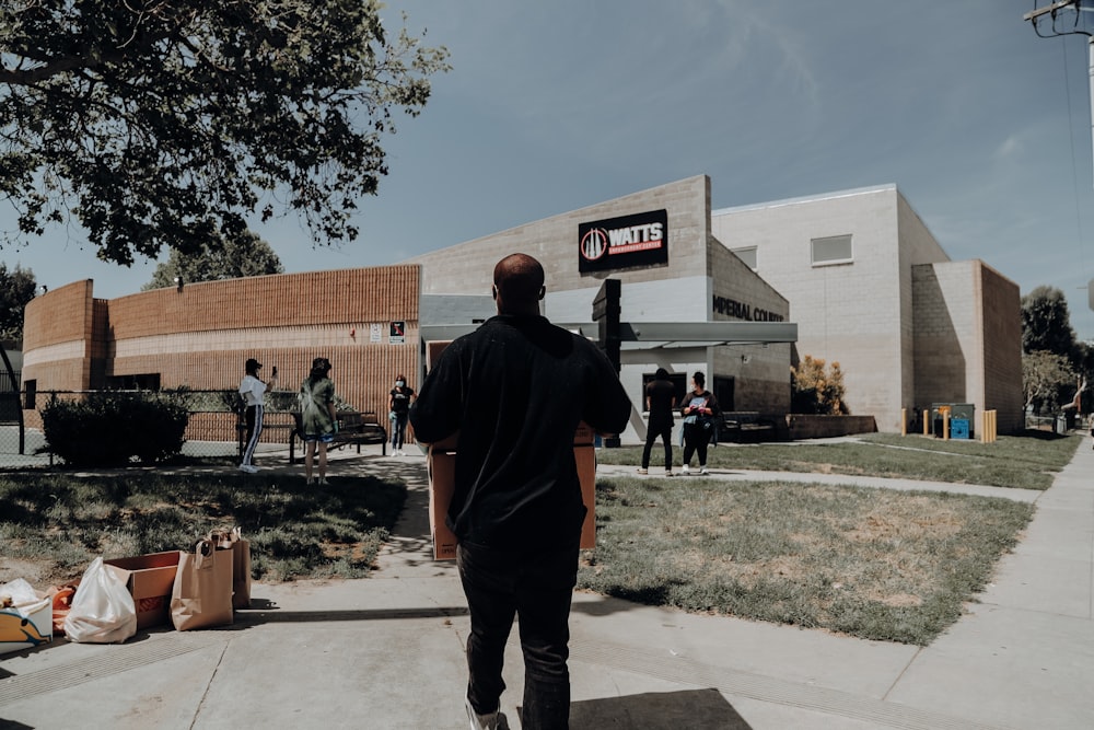 man in black hoodie standing near brown concrete building during daytime