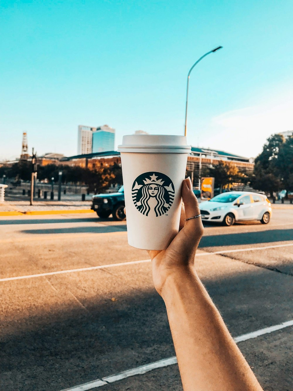 Persona sosteniendo un vaso desechable blanco y verde