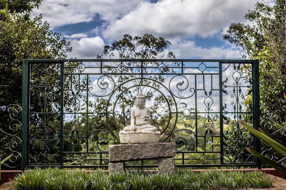 white statue of man on black metal fence