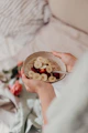 person holding stainless steel spoon and round brown bowl with food