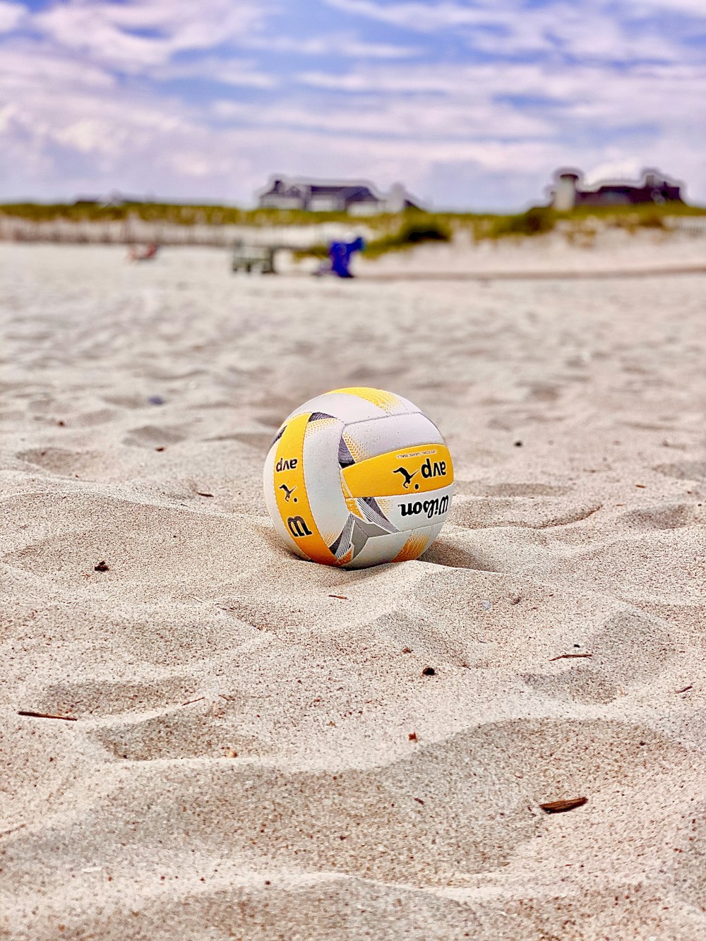 昼間の白い砂浜の黄色と白のバレーボール