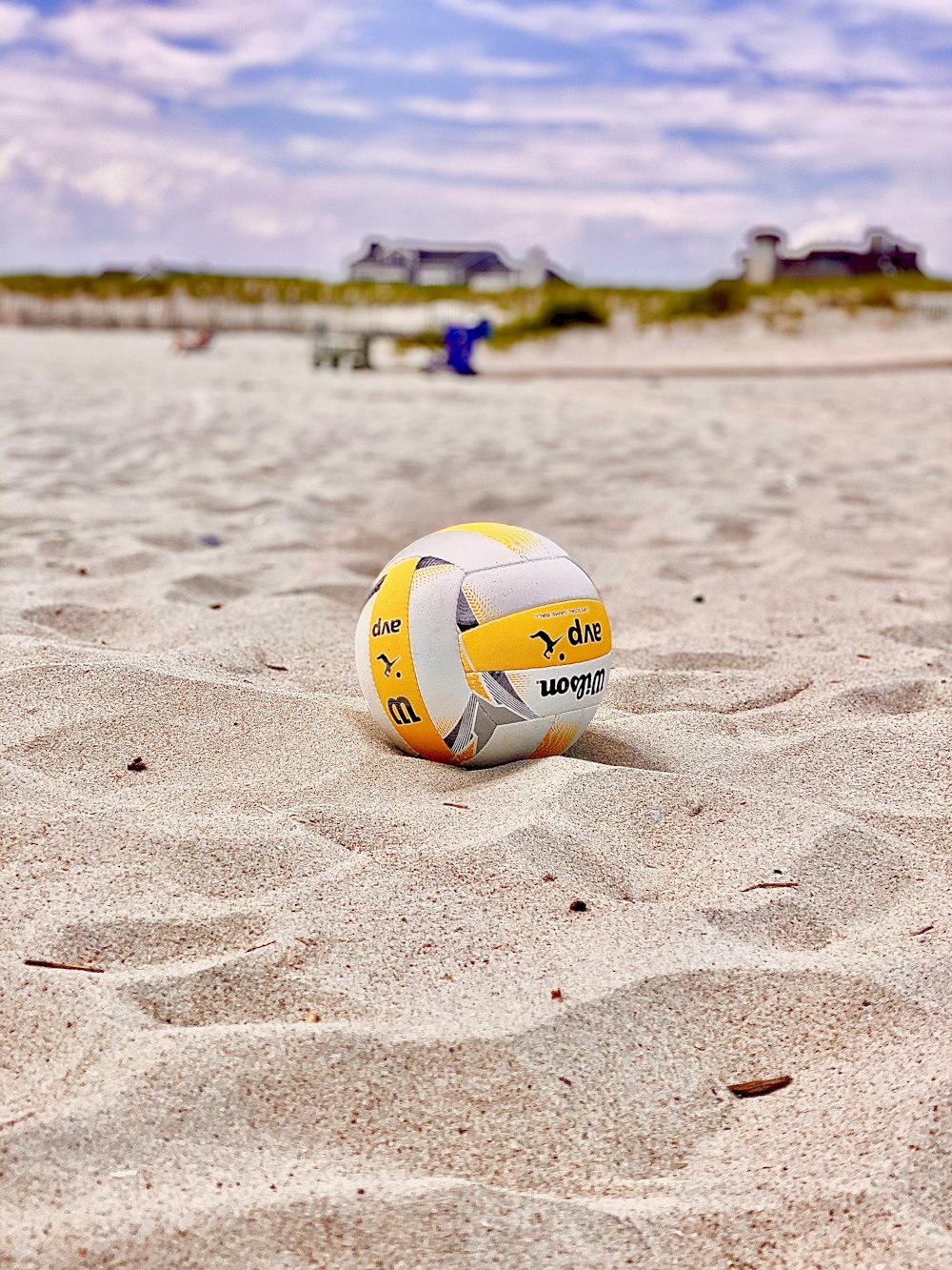 Voleibol amarillo y blanco sobre arena blanca durante el día