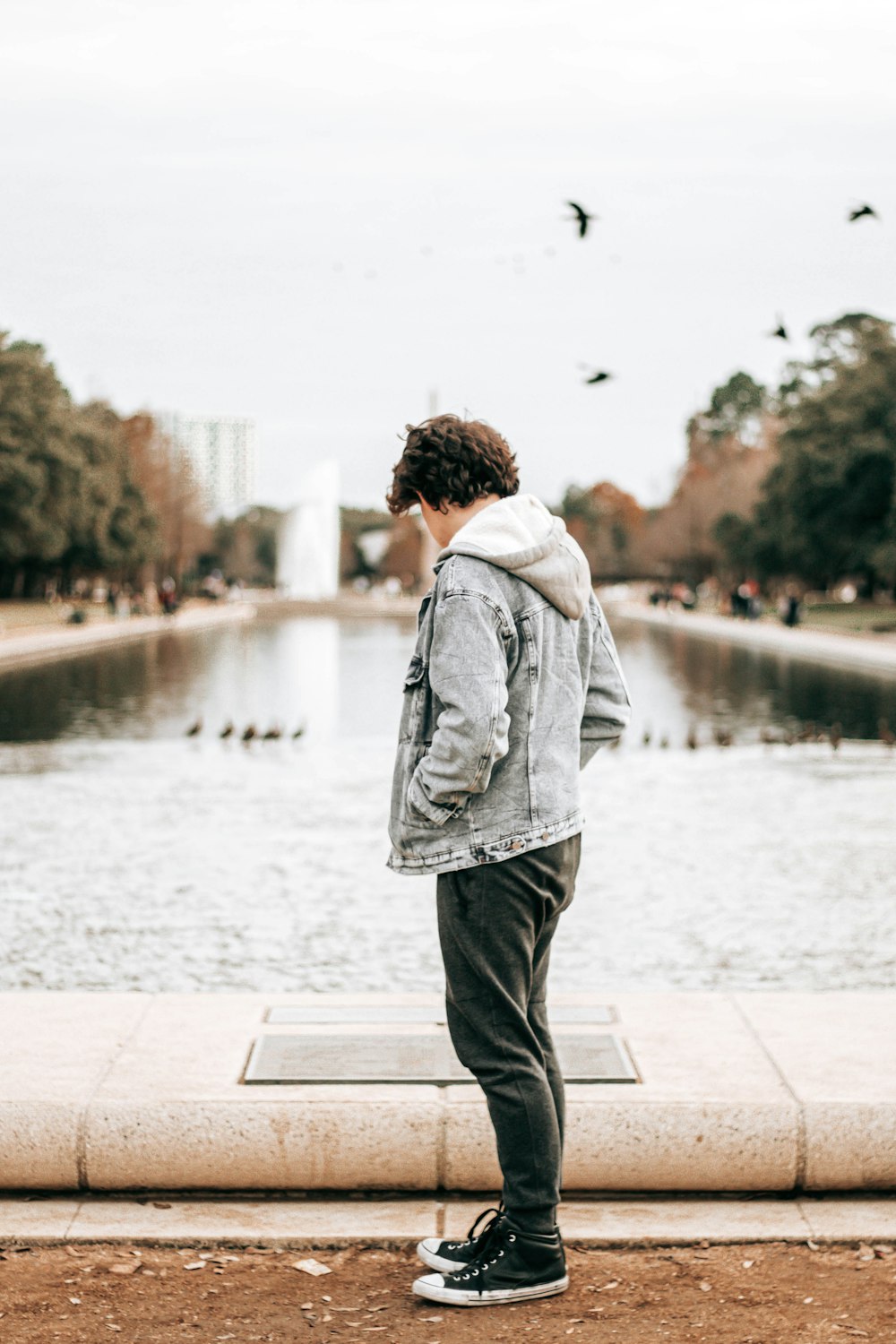 man in gray hoodie standing on gray concrete floor during daytime