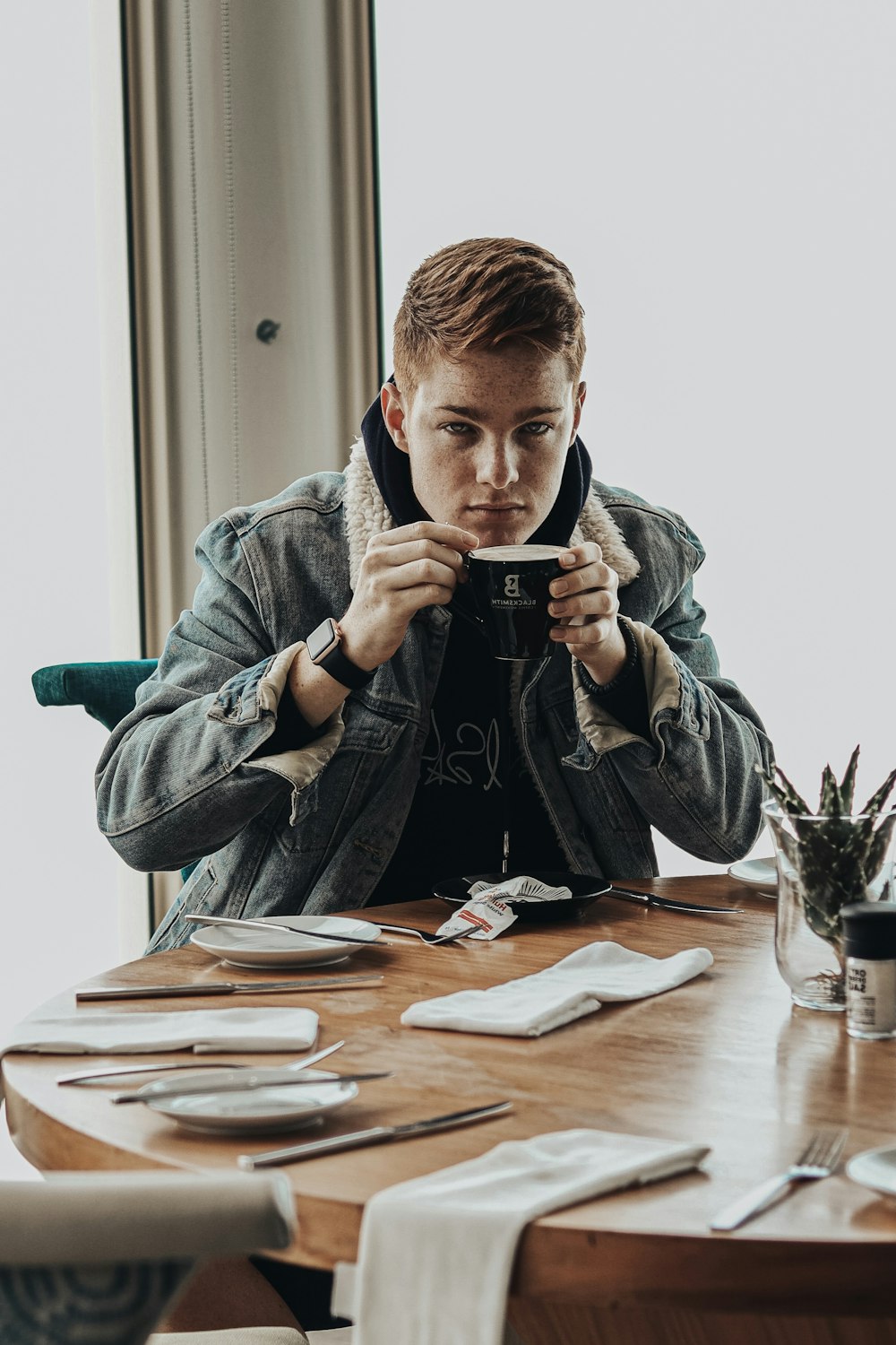 man in gray hoodie holding black ceramic mug