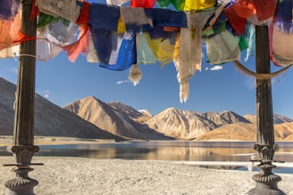 blue yellow and red textile on gray sand near lake and mountain during daytime