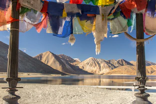 blue yellow and red textile on gray sand near lake and mountain during daytime