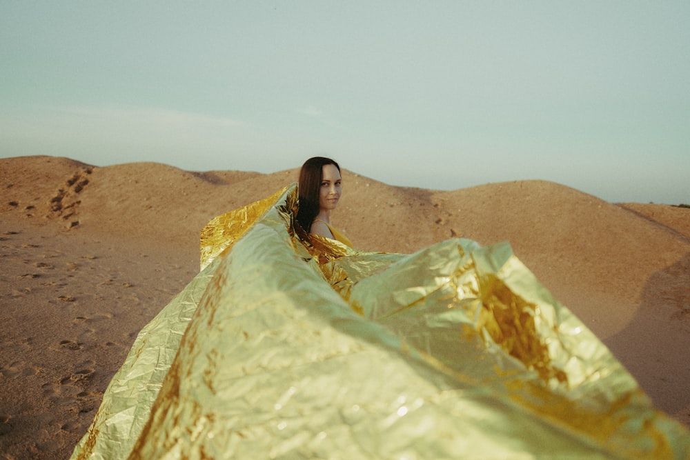 woman in yellow and green dress sitting on brown sand during daytime