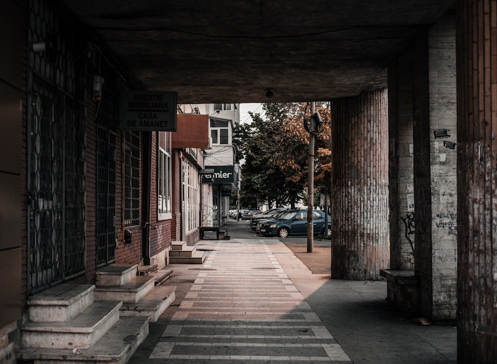 brown wooden pathway in between of red brick building during daytime