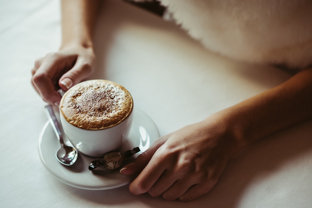 pessoa segurando caneca de cerâmica branca com café