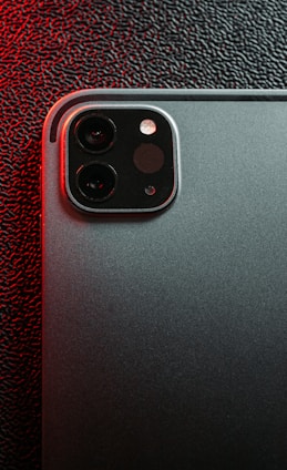 Close-up of a high-tech camera module glowing softly, set against a backdrop of foggy mountains at dawn.