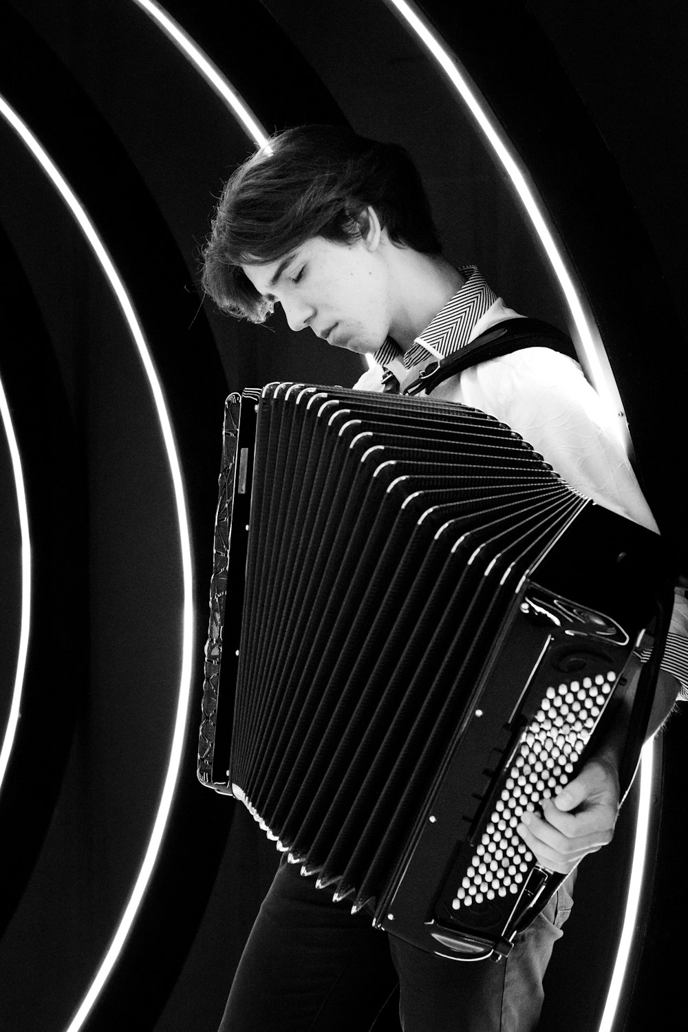 man in white shirt playing black and white accordion