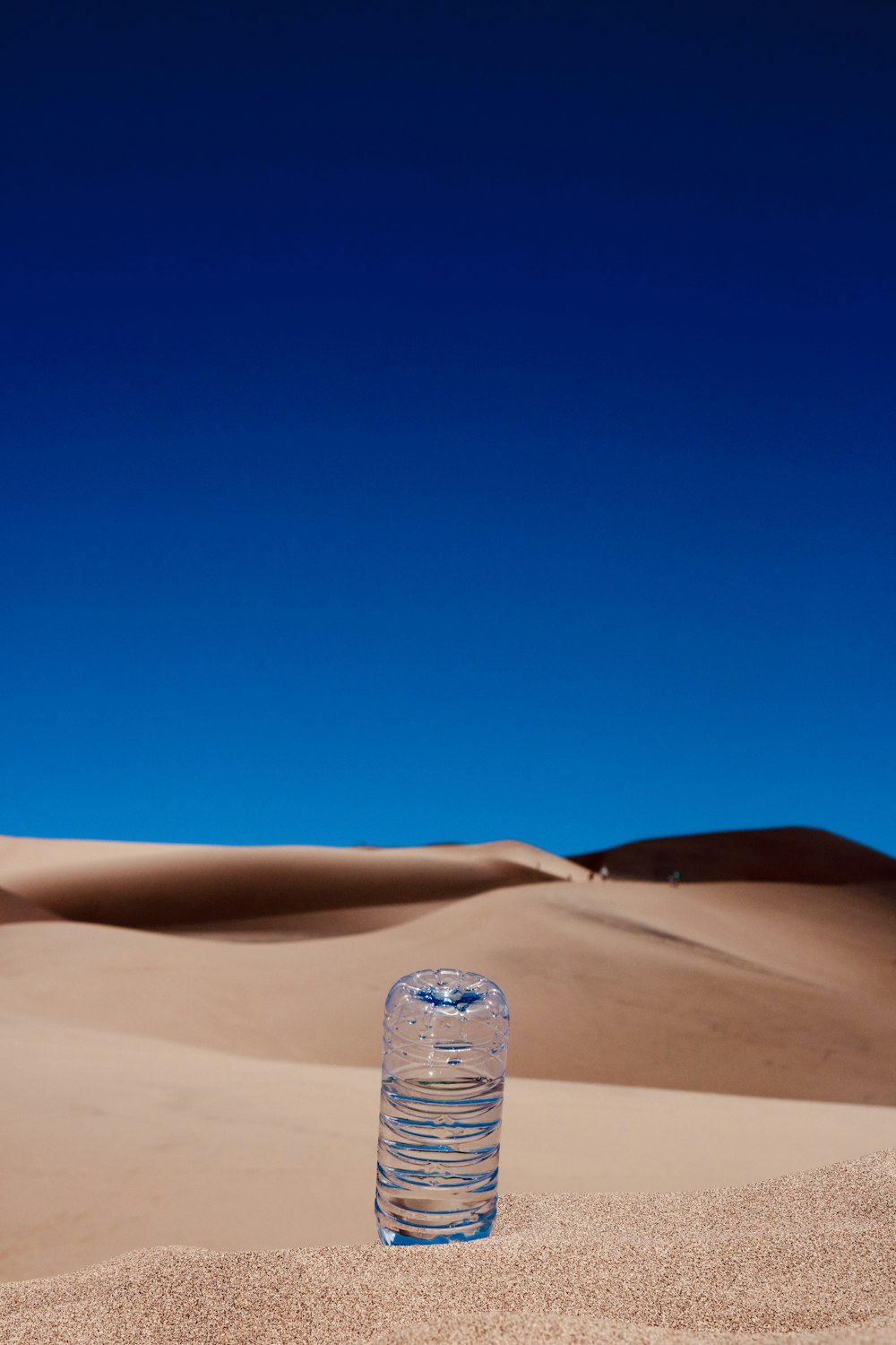bottiglia di plastica trasparente su sabbia marrone