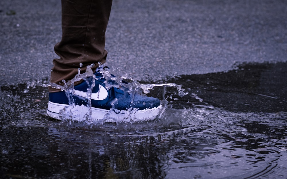 person in blue and white nike sneakers standing on water