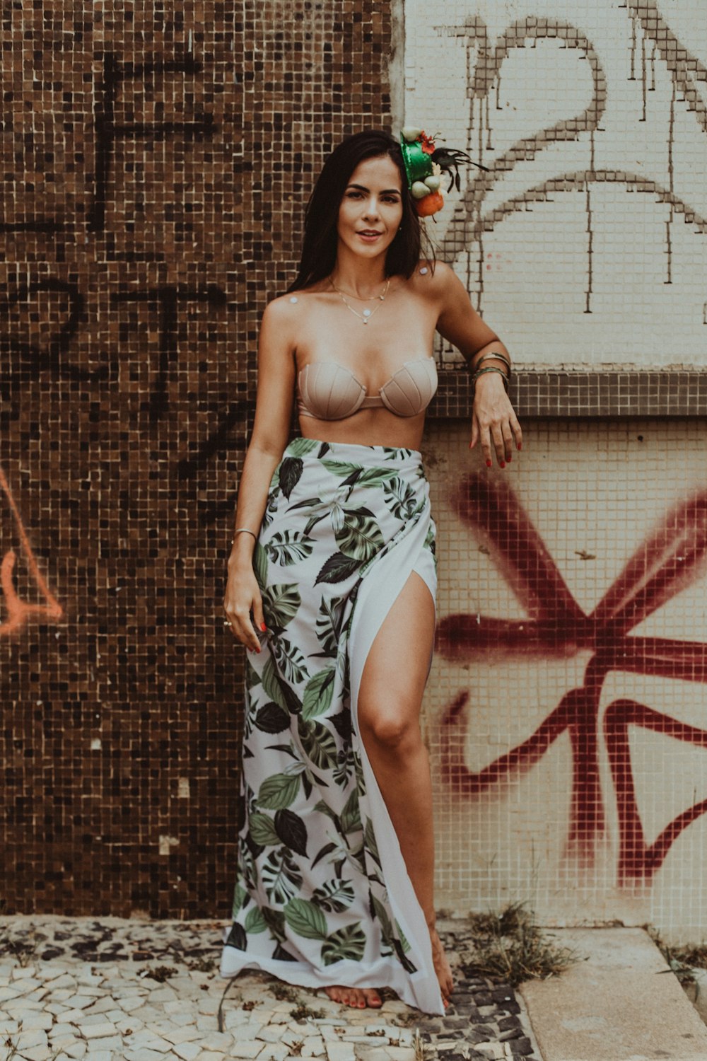 woman in green and white floral tube dress standing beside red and white wall