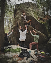 group of people in white long sleeve shirt and green pants standing on rocky ground