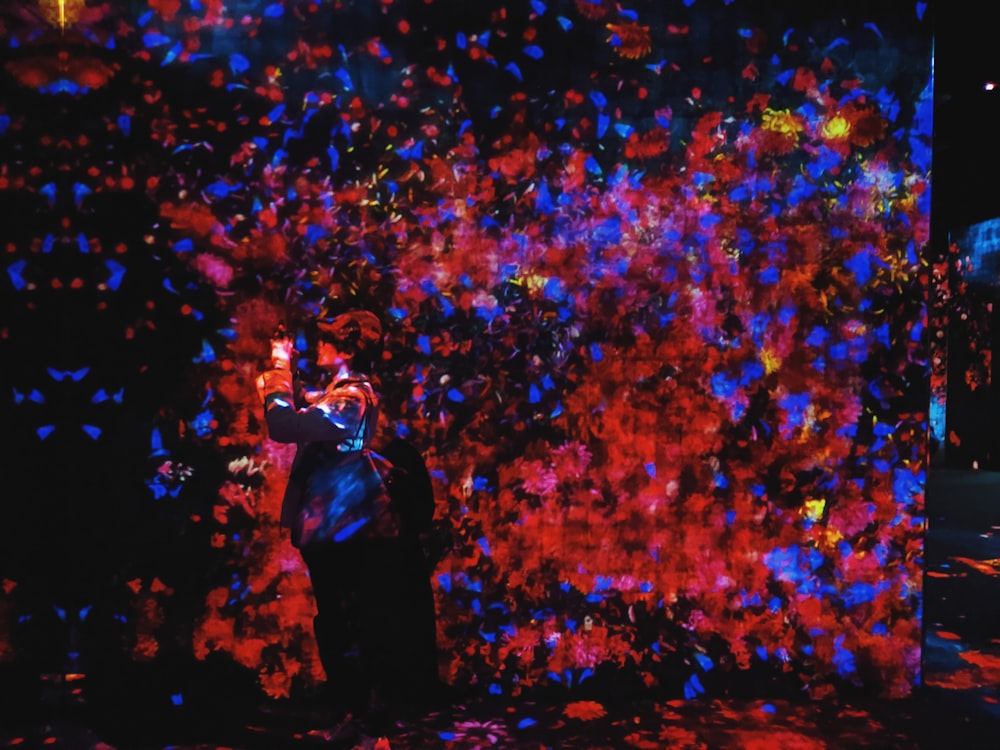 man in black jacket standing in front of blue and red lights