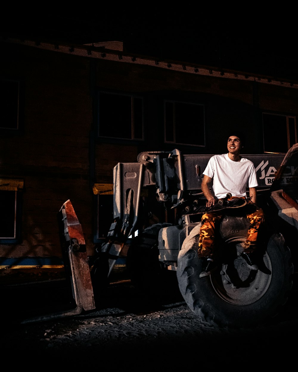 man in white dress shirt and black pants sitting on black tractor