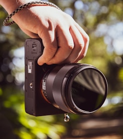 person holding black point and shoot camera