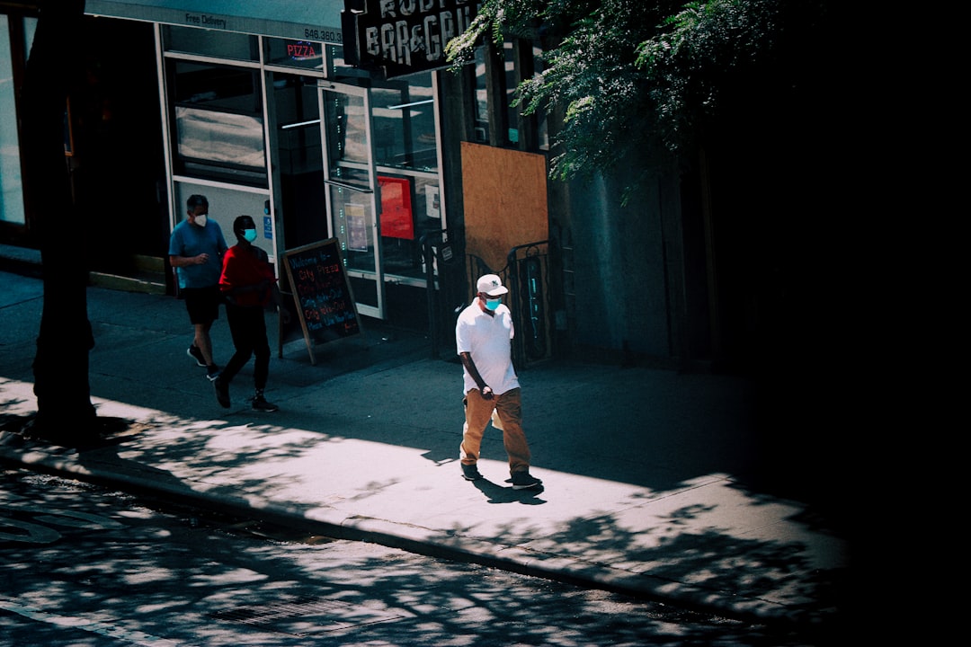 man in white t-shirt and red shorts walking on sidewalk during daytime