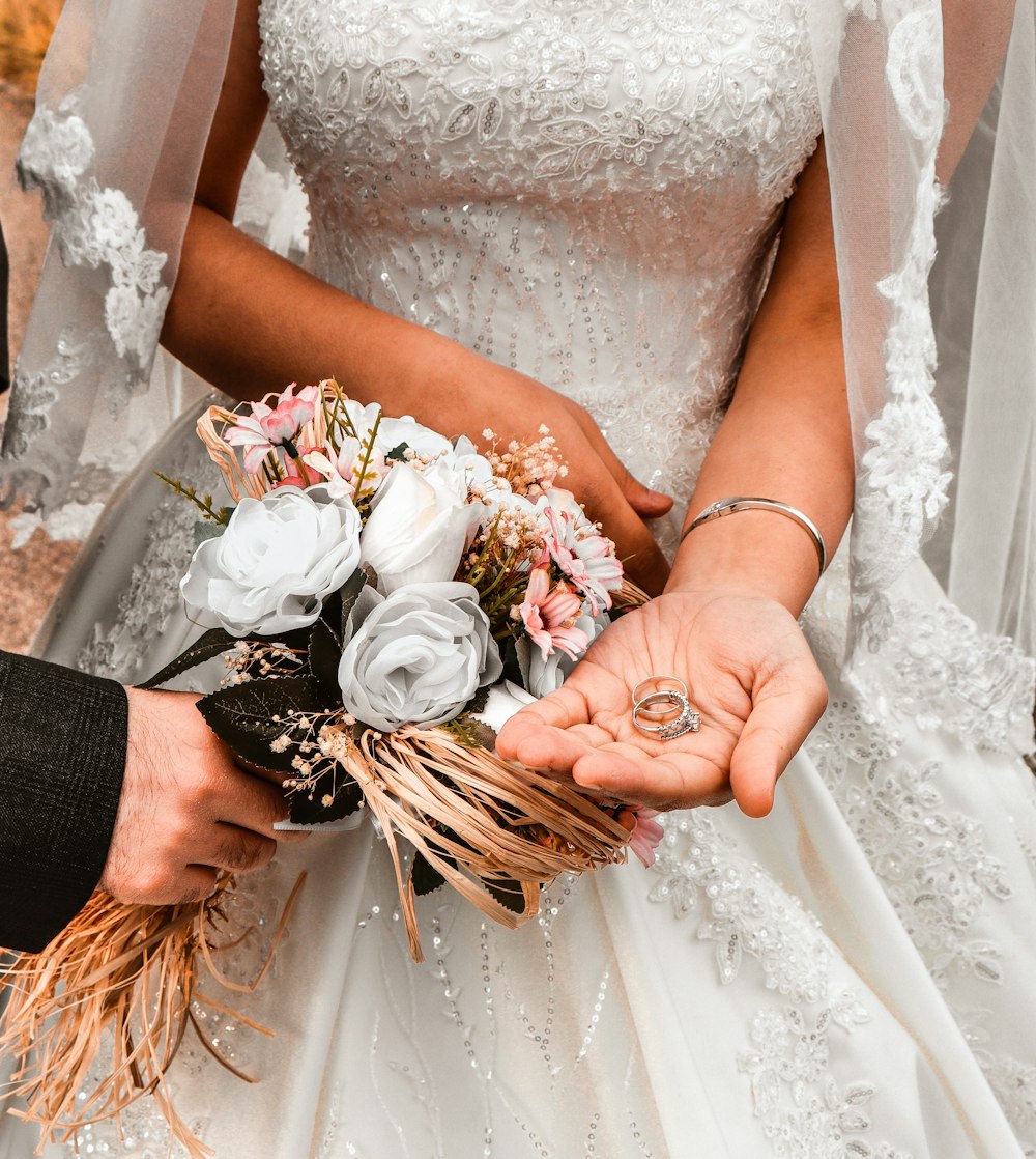 woman in white floral wedding dress holding bouquet of white roses