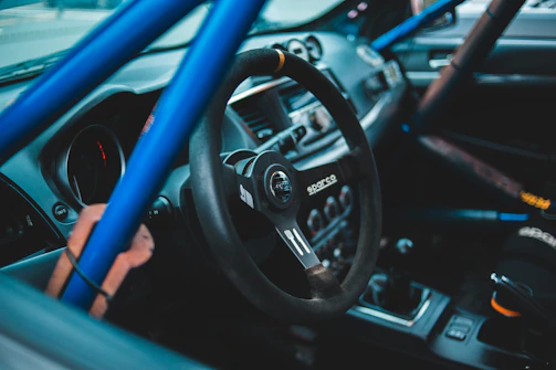 Interior shot showing the roll cage and safety harnesses inside the rally car.