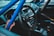 Inside the cabin of a car, featuring a Sparco steering wheel, racing seats, and a visible roll cage in a vibrant blue color. The dashboard includes various gauges and control elements, emphasizing a racing or sports car setup.