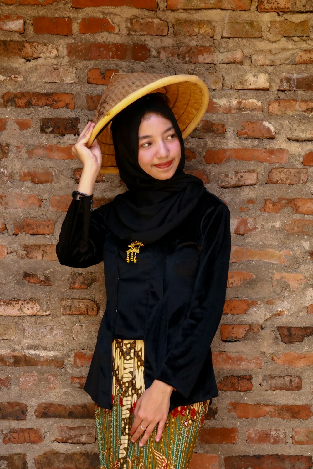 donna in camicia nera a maniche lunghe che indossa cappello di paglia marrone