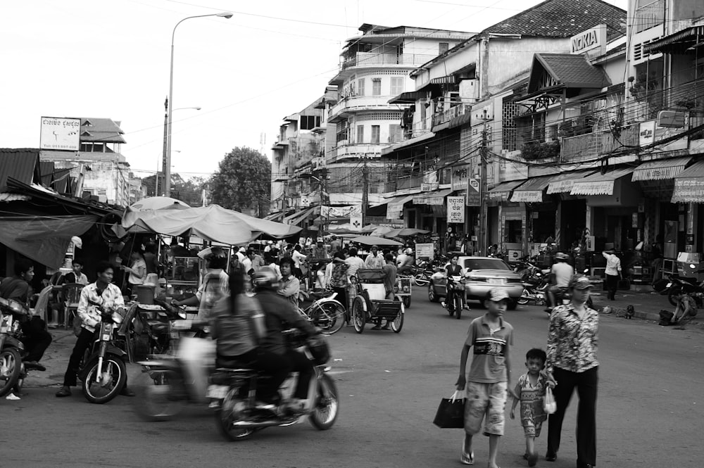 Foto en escala de grises de personas montando motocicleta en la carretera