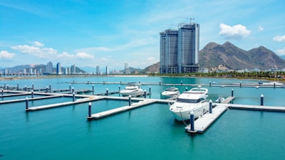 A panoramic view of a marina filled with motor yachts and catamarans under a clear blue sky.