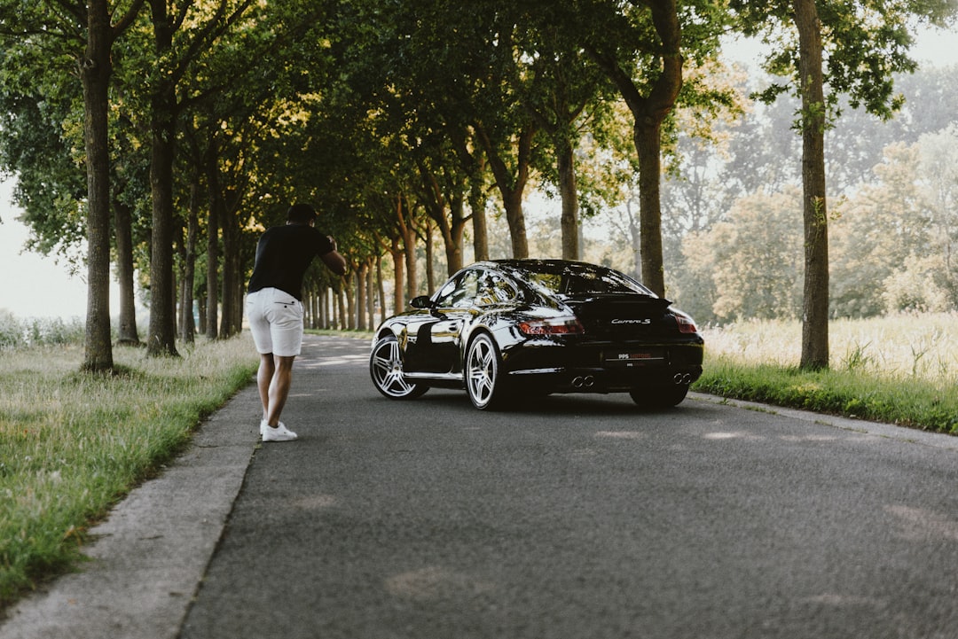 woman in white shirt and white shorts standing beside black bmw coupe during daytime