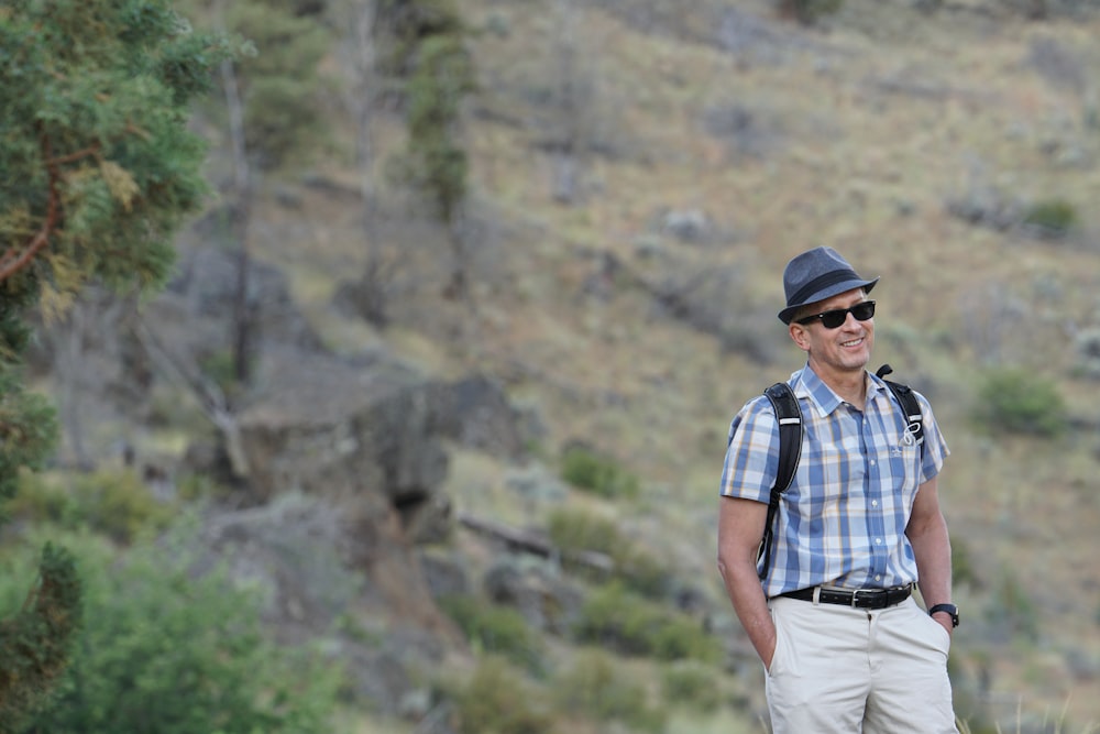 man in blue white and black plaid button up shirt and white pants standing on brown