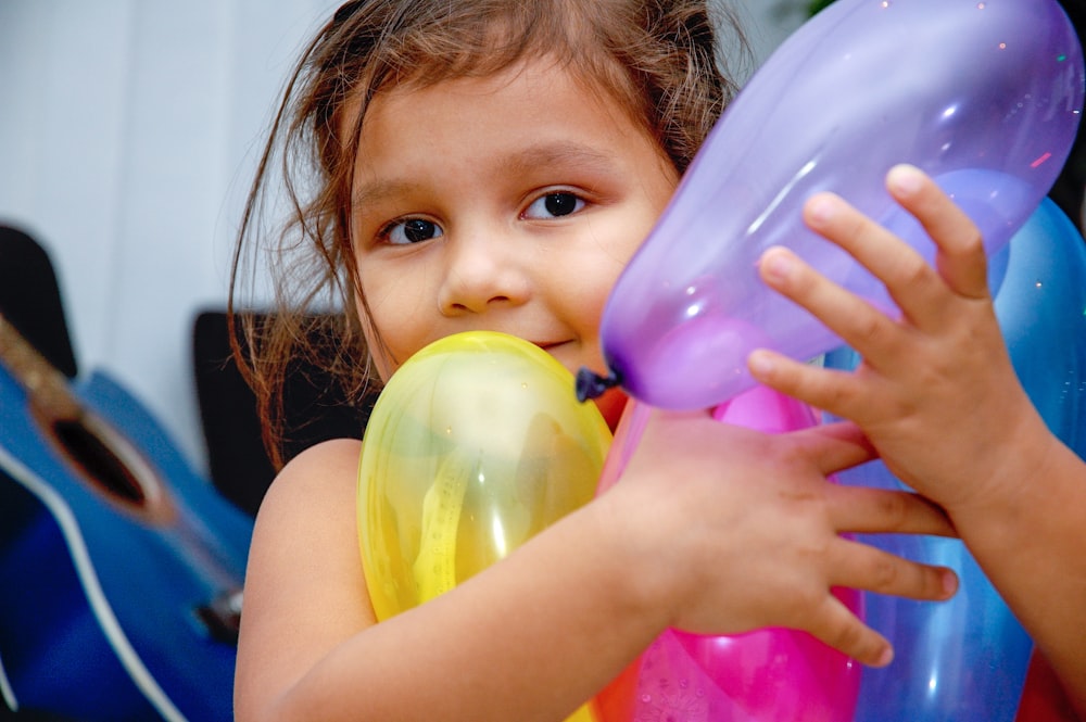 girl holding yellow and purple balloon