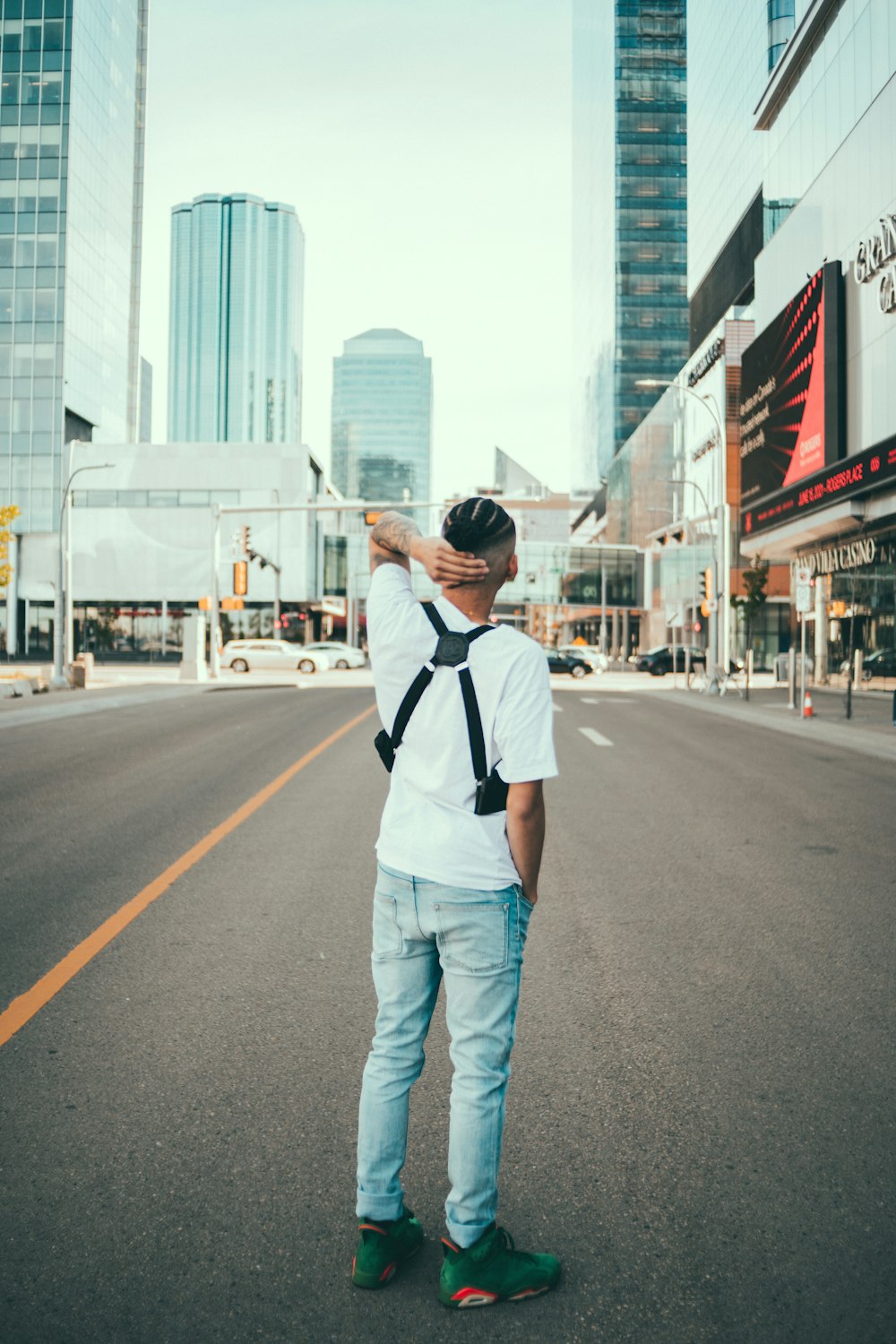 man in white and black polo shirt standing on road during daytime