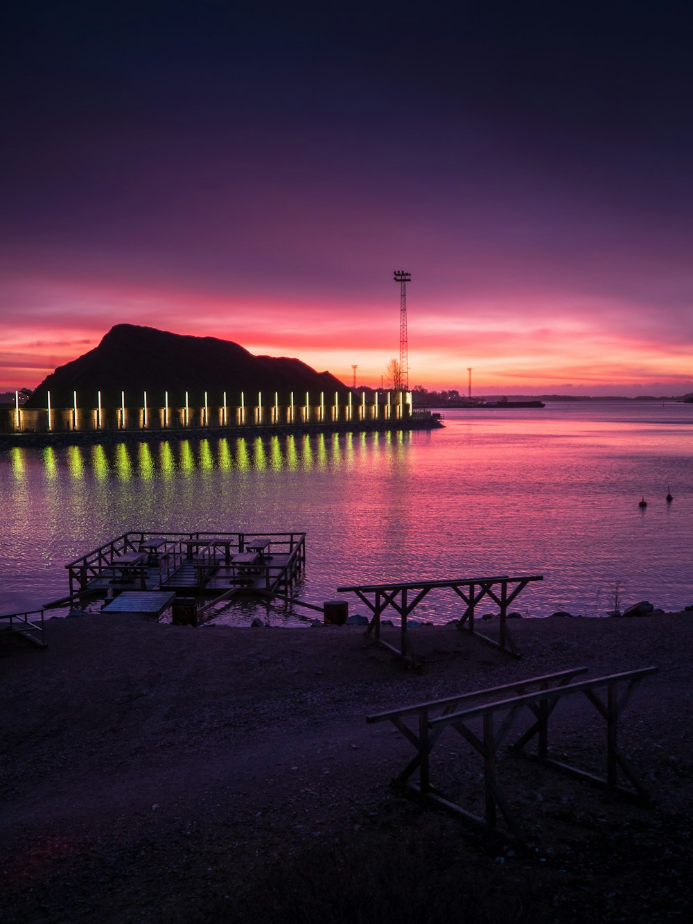 silhouette of two people sitting on bench near body of water during sunset