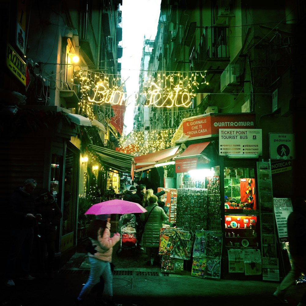 woman in black jacket holding pink umbrella walking on sidewalk during daytime